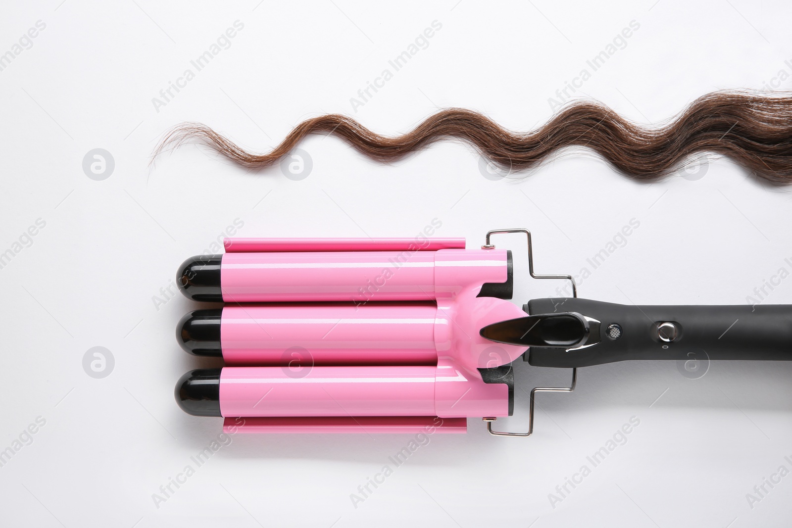 Photo of Modern triple curling iron and brown hair lock on white background, top view