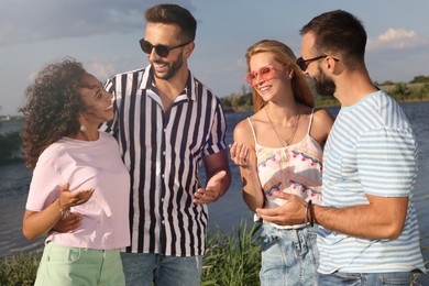 Group of friends having fun near river at summer party