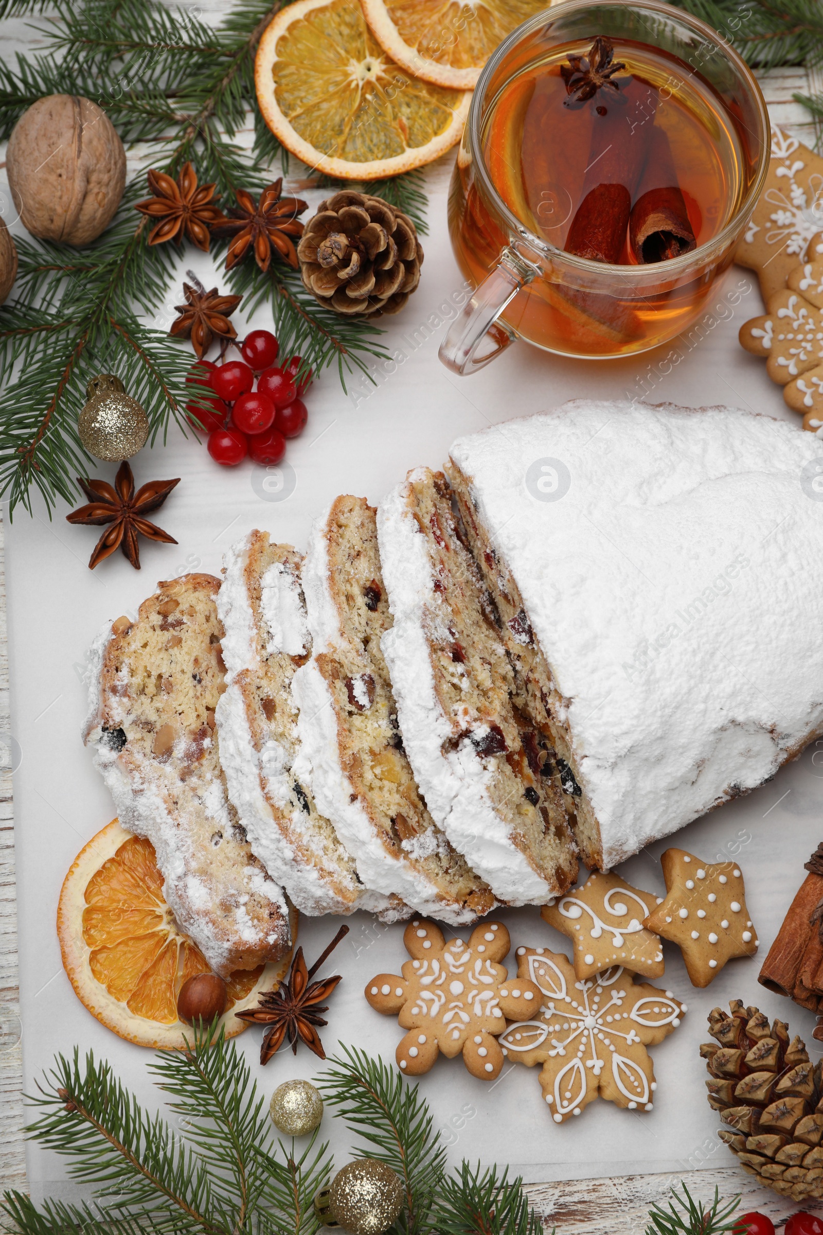 Photo of Traditional Christmas Stollen with icing sugar on white table, flat lay