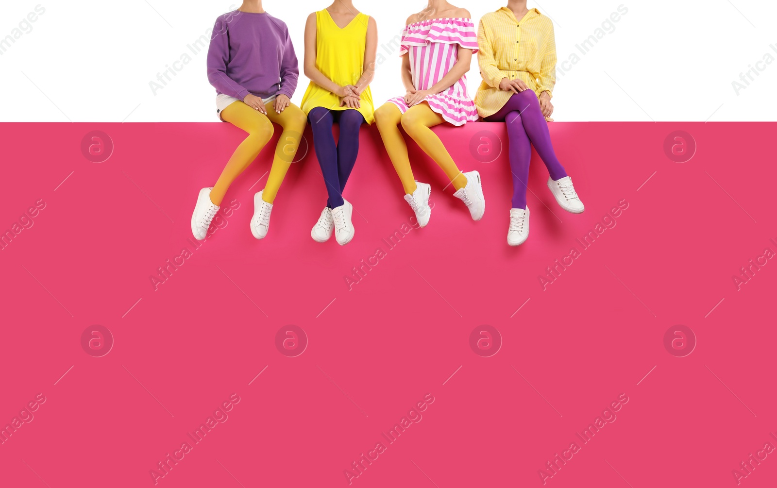 Photo of Group of women wearing bright tights and stylish shoes sitting on color background, closeup