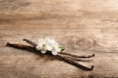 Photo of Vanilla sticks and flowers on wooden background