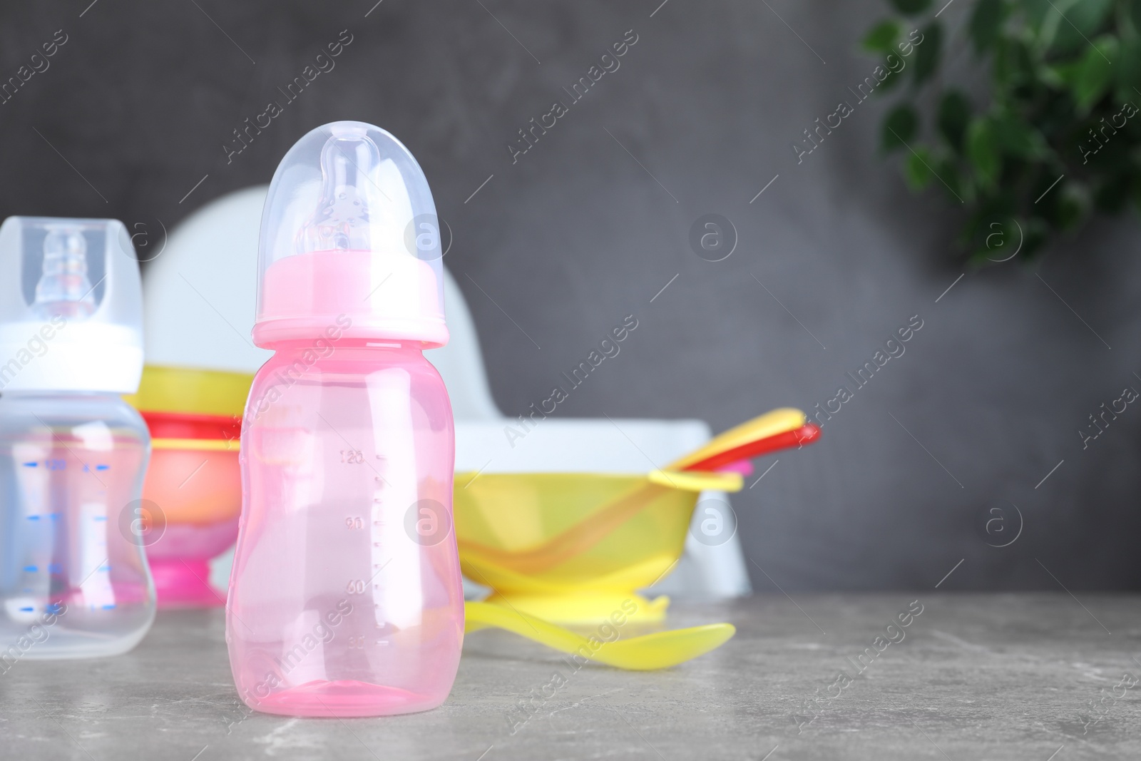 Photo of Bright child's dishware on grey table indoors. Space for text