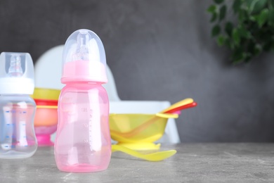 Bright child's dishware on grey table indoors. Space for text