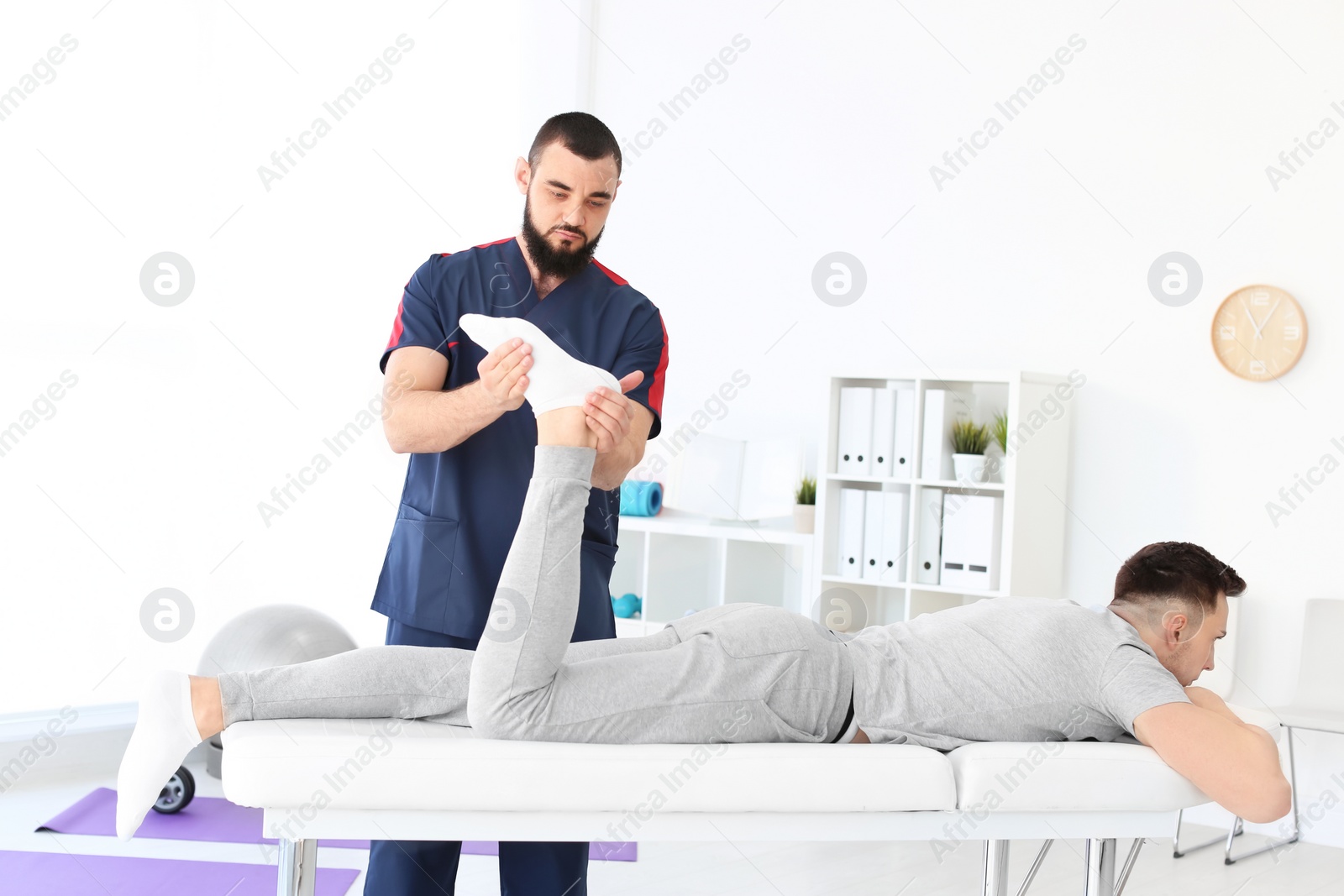 Photo of Physiotherapist working with young male patient in clinic