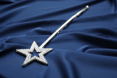 Photo of Beautiful silver magic wand on blue fabric