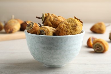 Photo of Bowl with tasty dried persimmon fruits on wooden table
