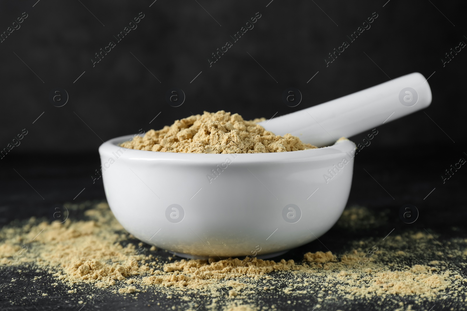 Photo of Mortar with mustard powder on black table