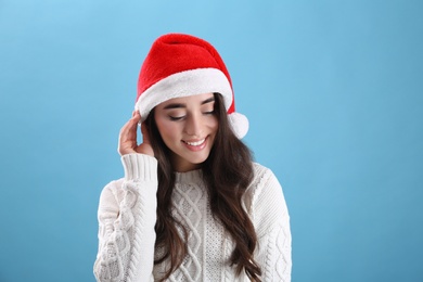 Photo of Beautiful woman wearing Santa Claus hat on light blue background