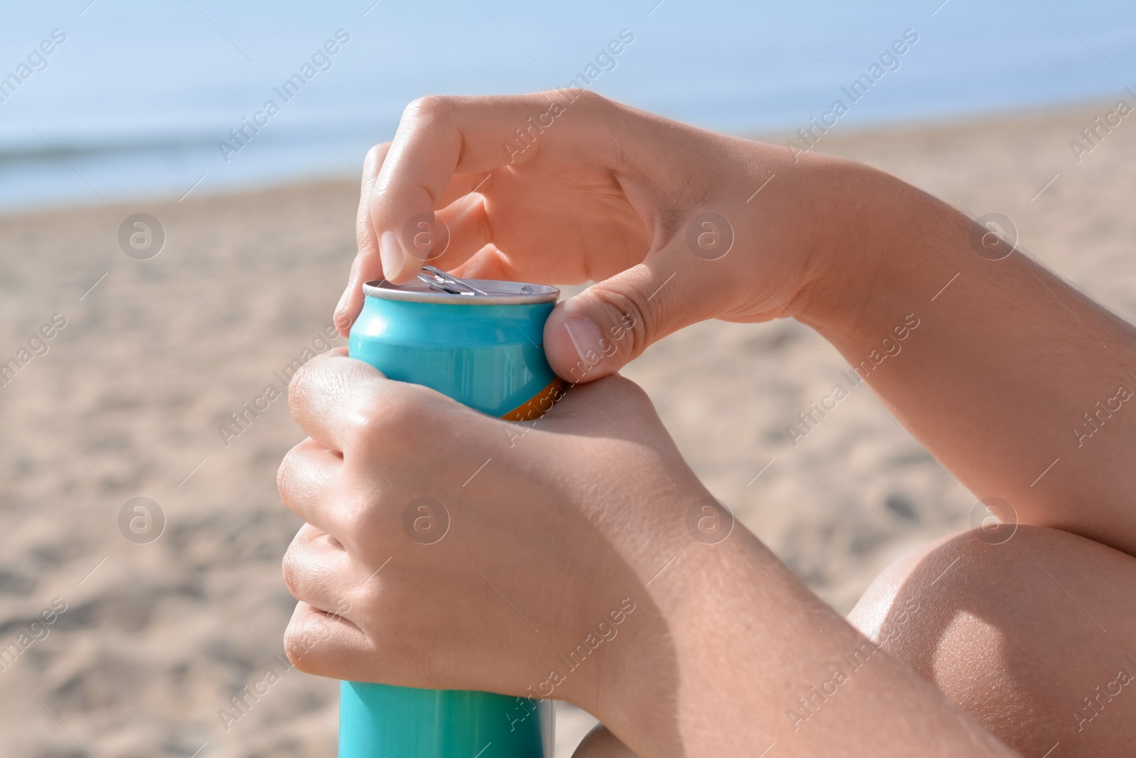 Photo of Woman opening aluminum can with beverage on beach, closeup