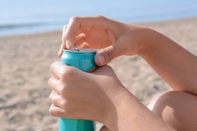 Photo of Woman opening aluminum can with beverage on beach, closeup