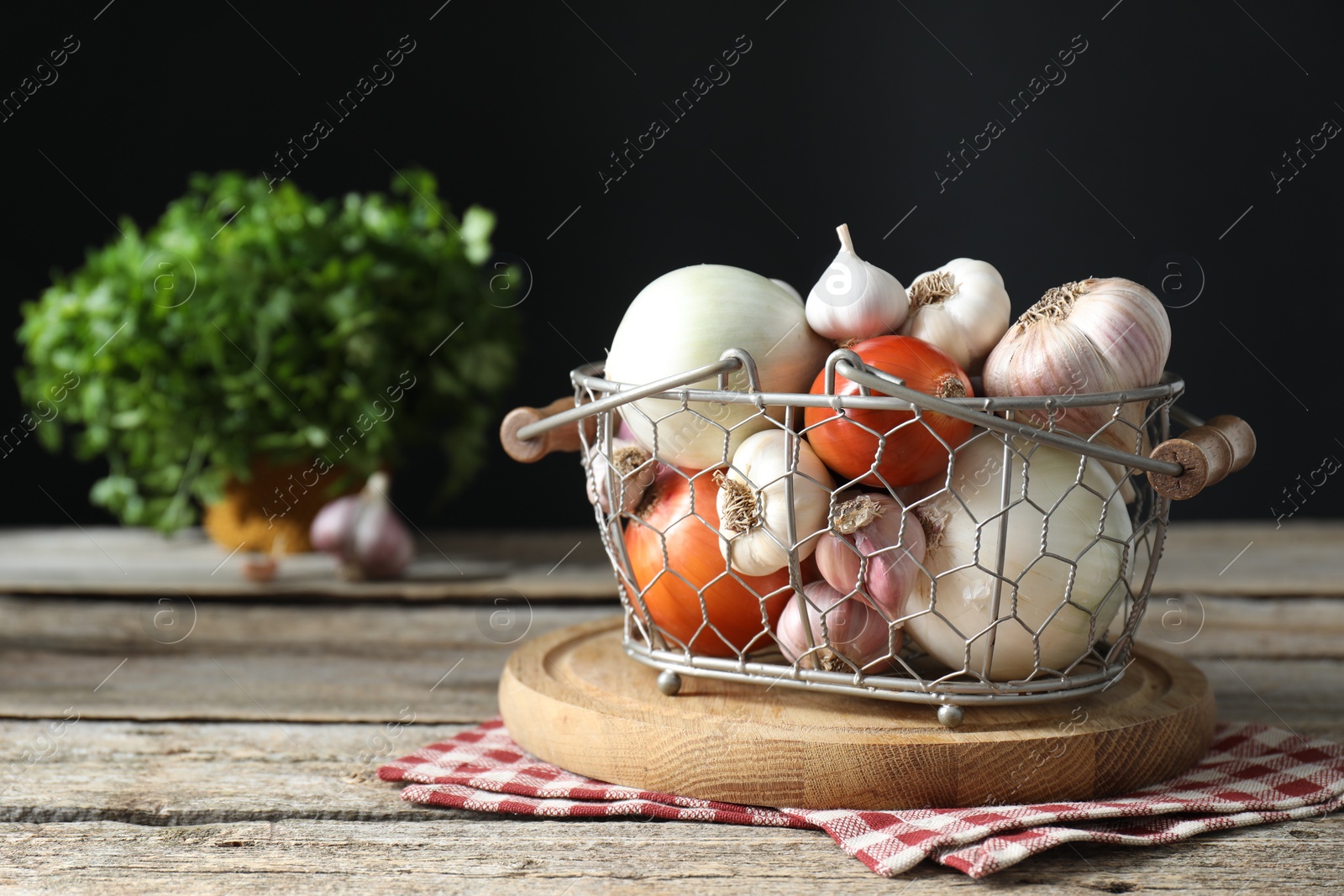 Photo of Fresh raw garlic and onions in metal basket on wooden table