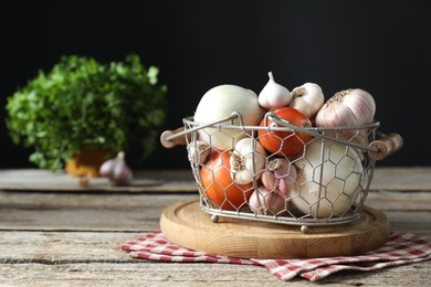 Fresh raw garlic and onions in metal basket on wooden table