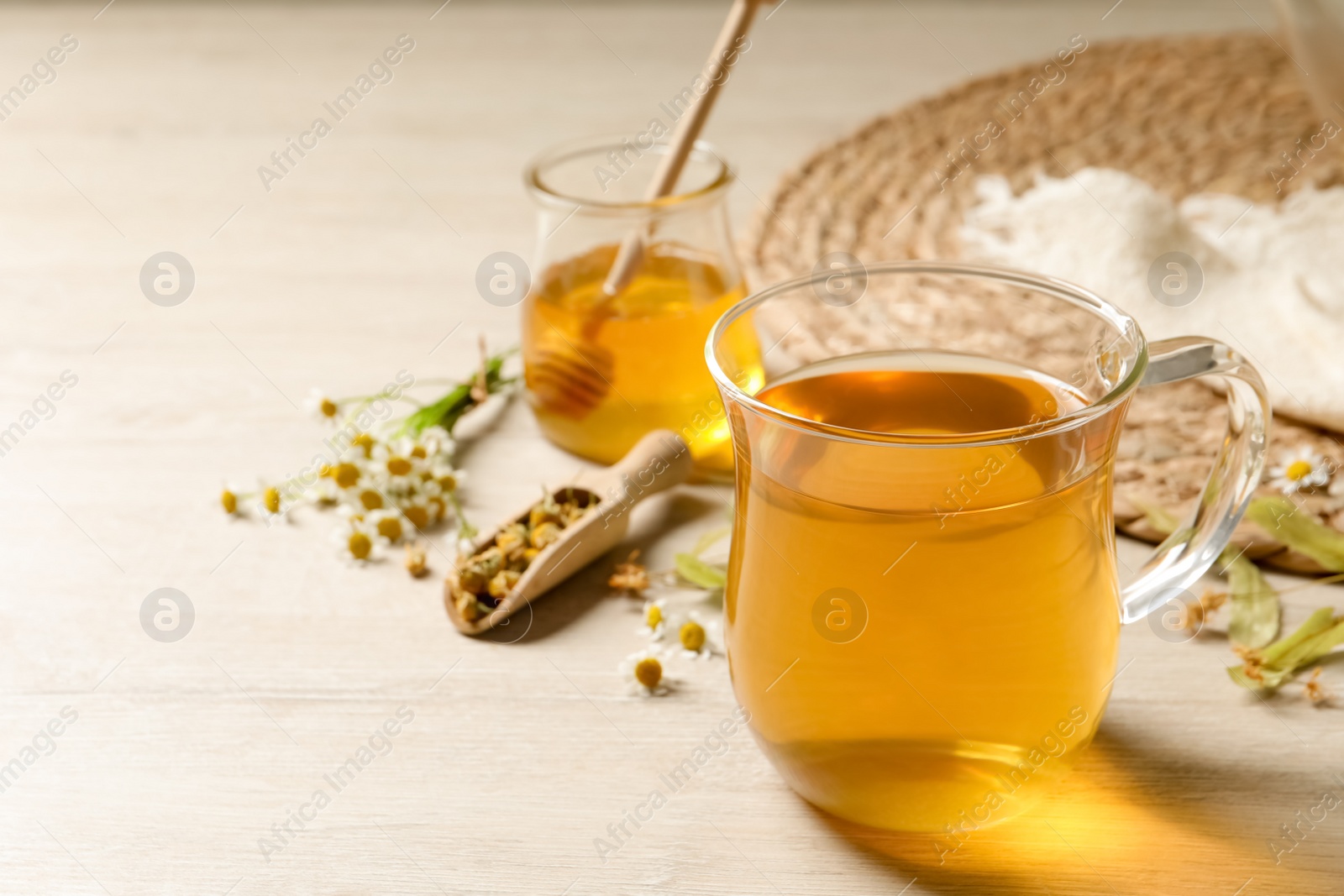 Photo of Freshly brewed tea and dried herbs on white wooden table. Space for text