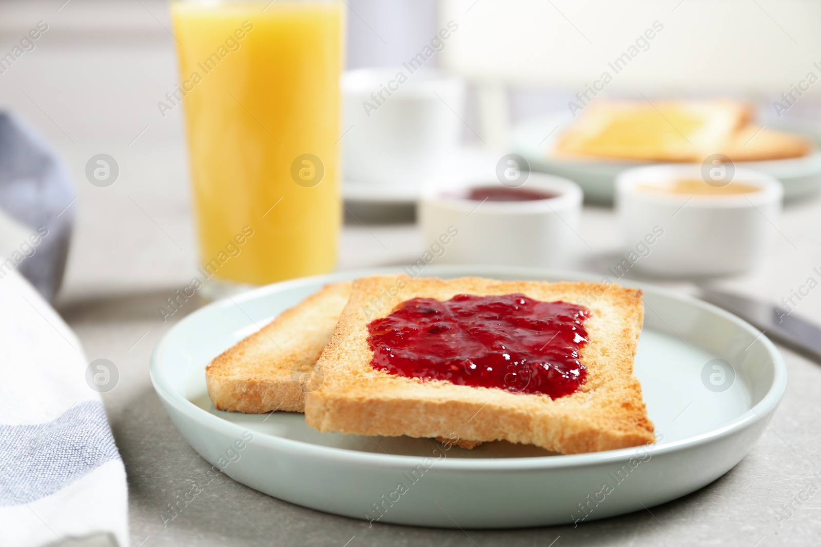 Photo of Fresh toasts with jam for breakfast on light grey table