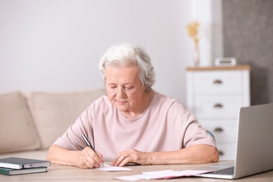 Portrait of senior woman filling out lottery ticket at table