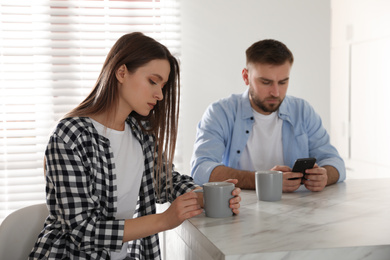 Young man preferring smartphone over his girlfriend at home. Relationship problems