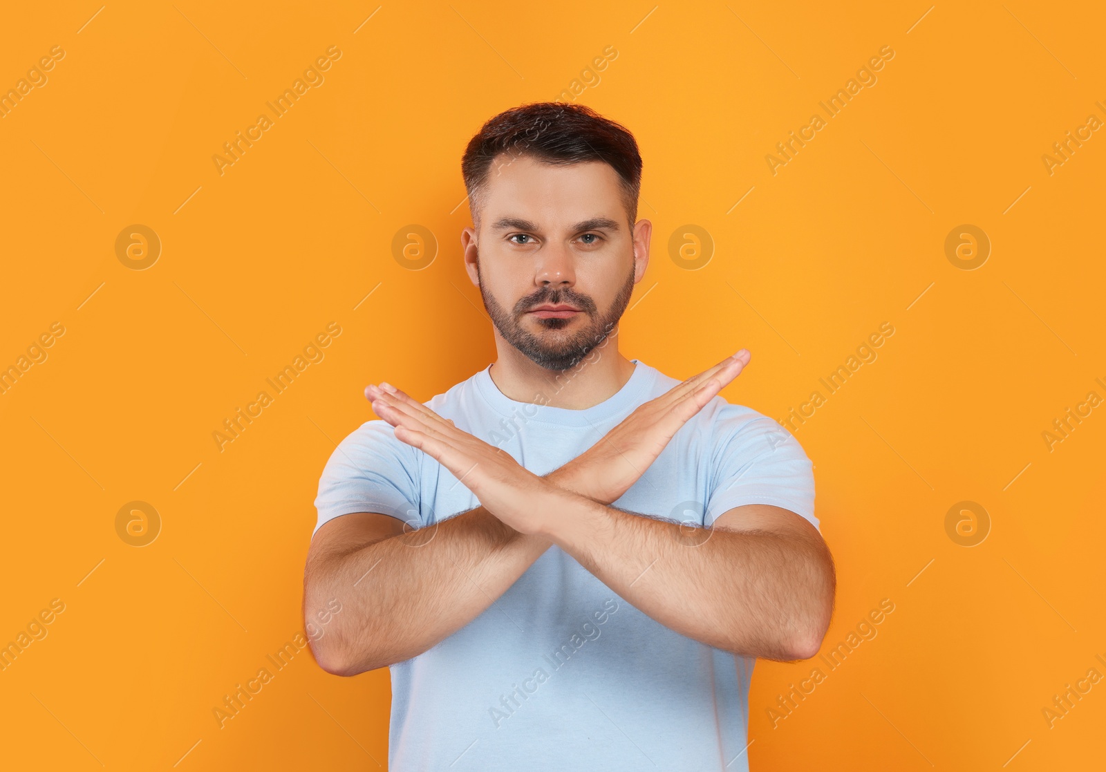 Photo of Handsome man with crossed hands on orange background. Stop gesture