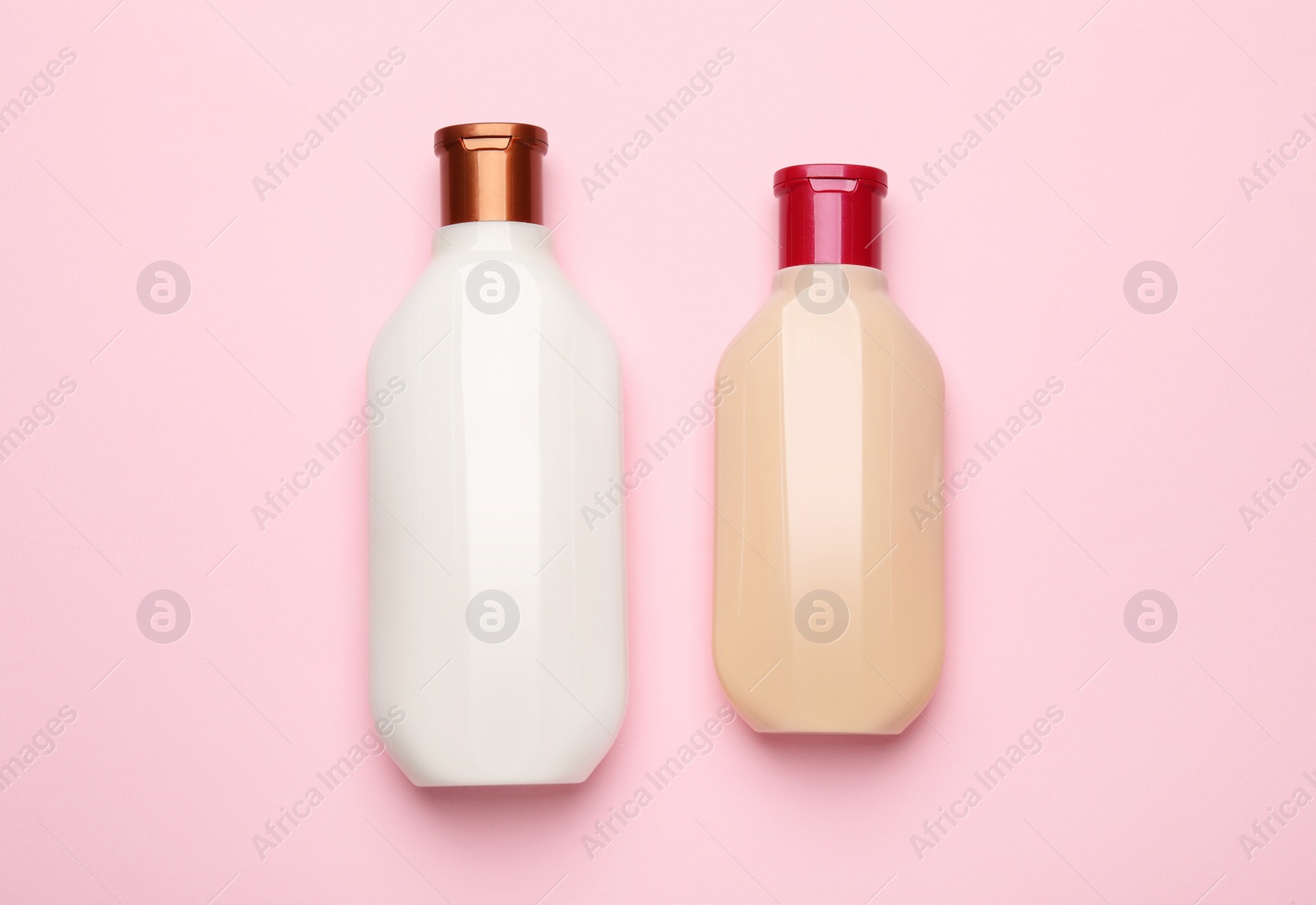 Photo of Bottles of shampoo on pink background, flat lay