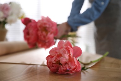 Florist making beautiful bouquet at table, focus on peony