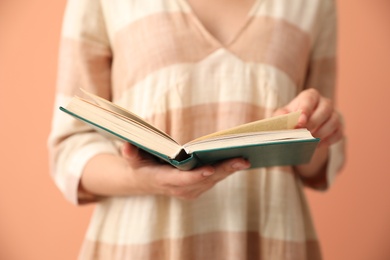 Young woman with book on coral background, closeup