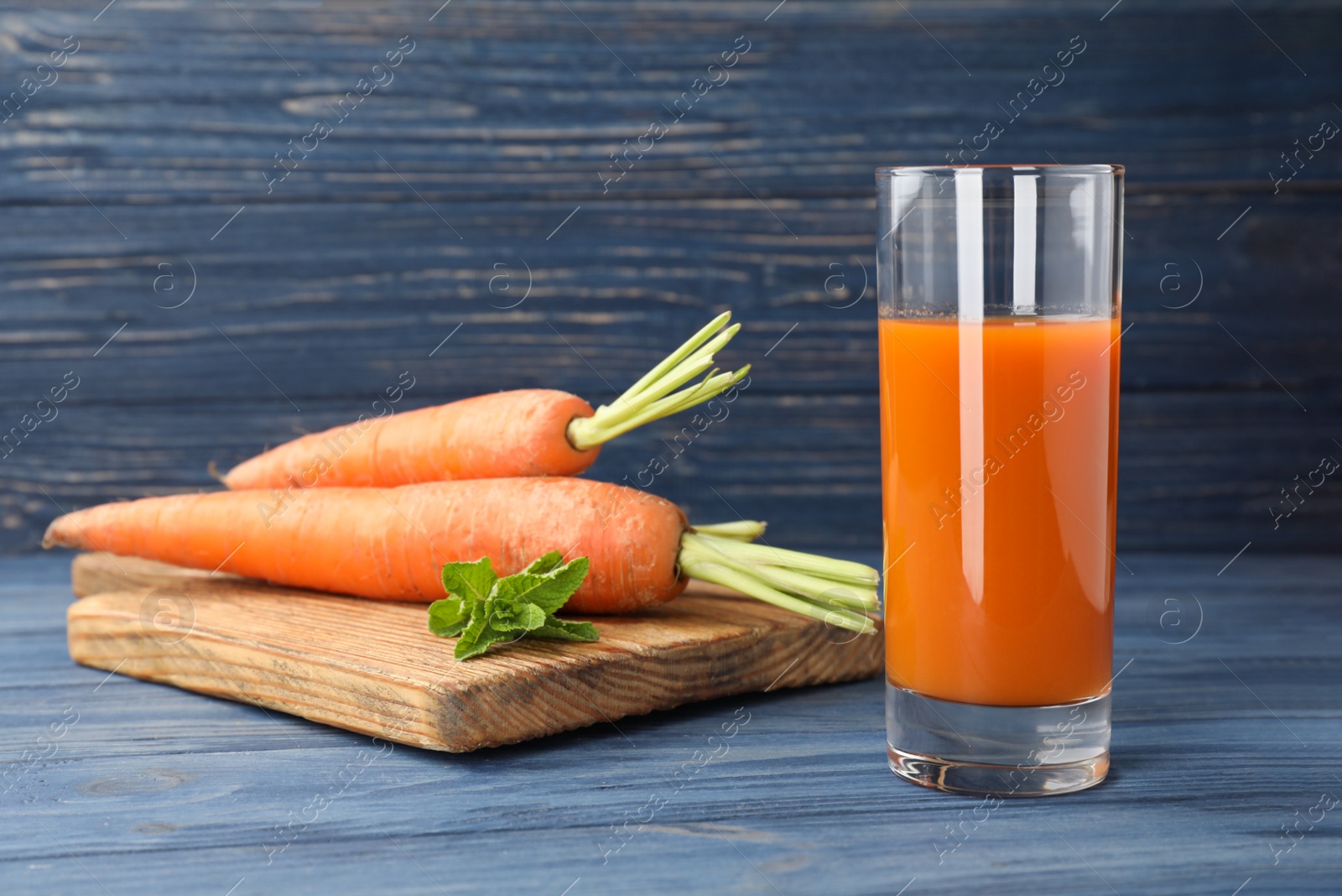 Photo of Glass of drink and carrots on wooden table, space for text