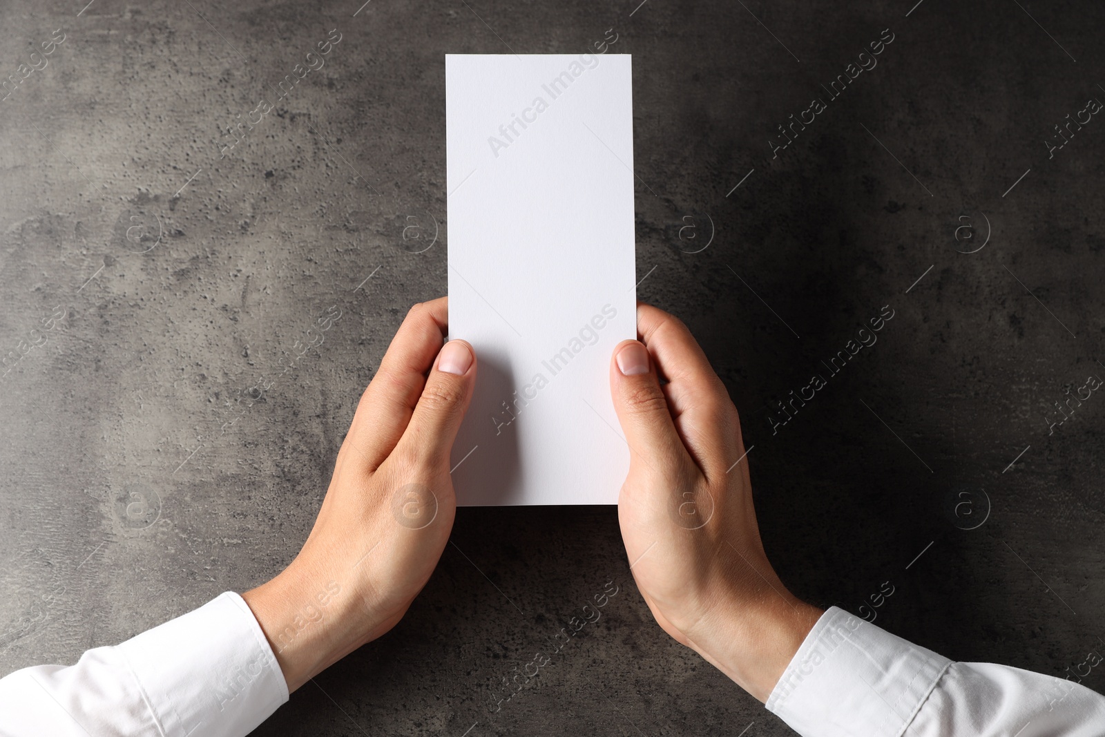 Photo of Man holding blank card at black textured table, top view. Mockup for design