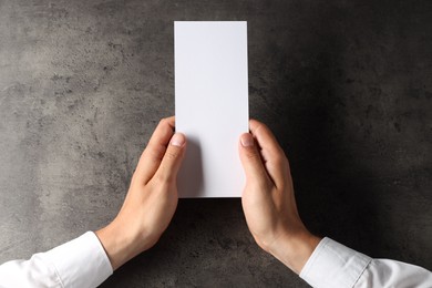 Photo of Man holding blank card at black textured table, top view. Mockup for design