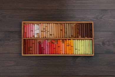 Photo of Drawing pastel set in box on wooden background, top view