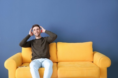 Handsome young man listening to music on sofa, indoors