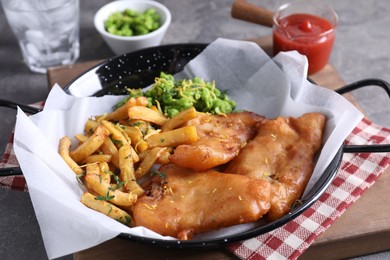 Photo of Tasty fish, chips, sauce and peas on grey table, closeup