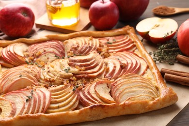 Freshly baked apple pie with nuts and ingredients on wooden table, closeup