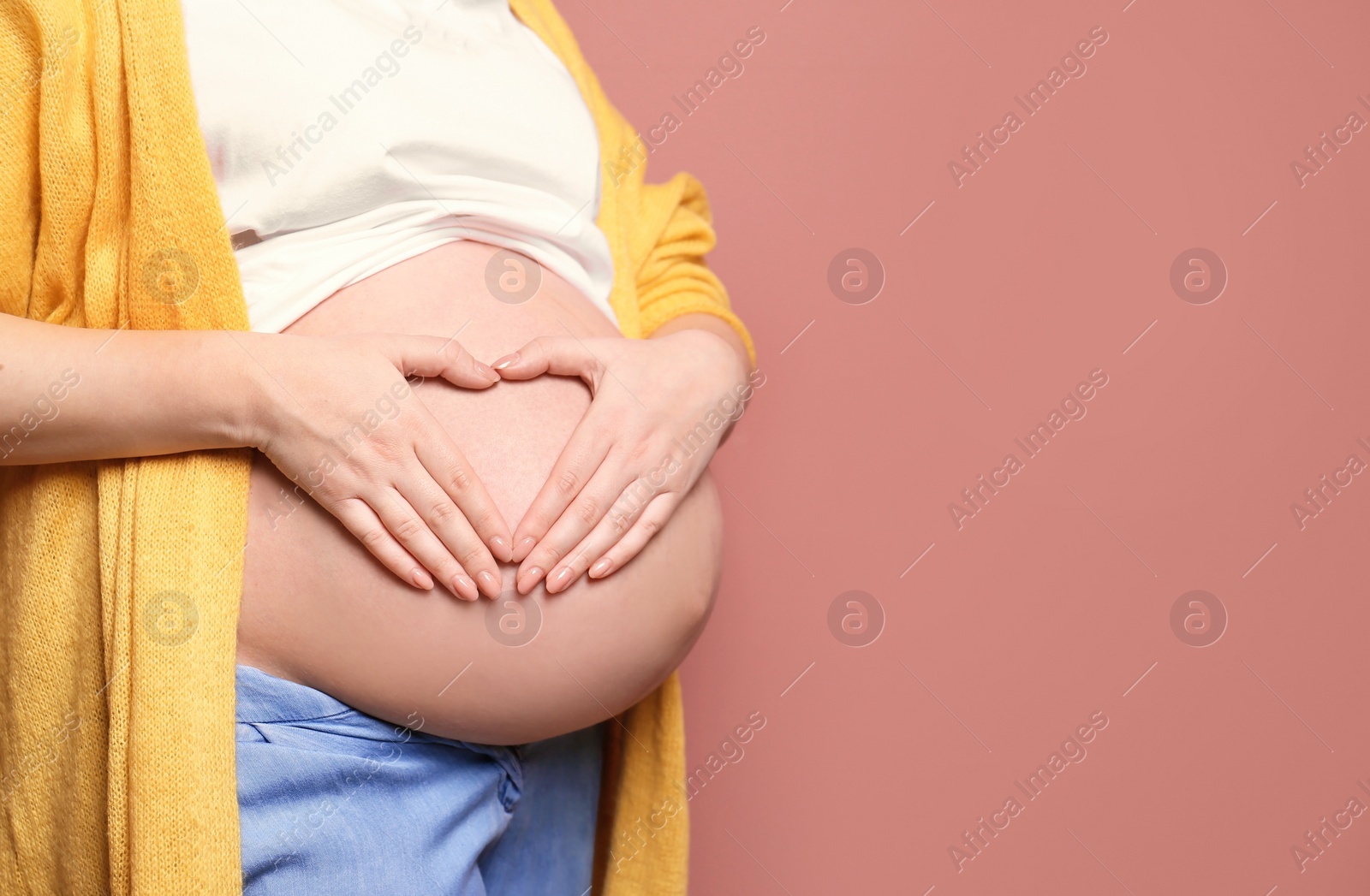 Photo of Young pregnant woman in casual clothes on color background