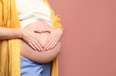 Young pregnant woman in casual clothes on color background