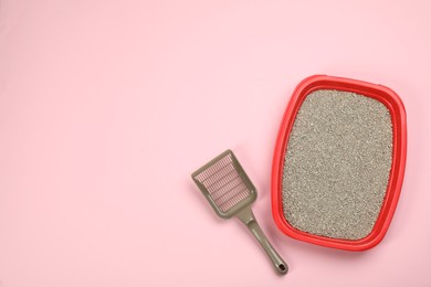 Cat litter tray with filler and scoop on pink background, flat lay. Space for text