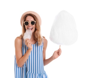 Happy young woman eating cotton candy on white background