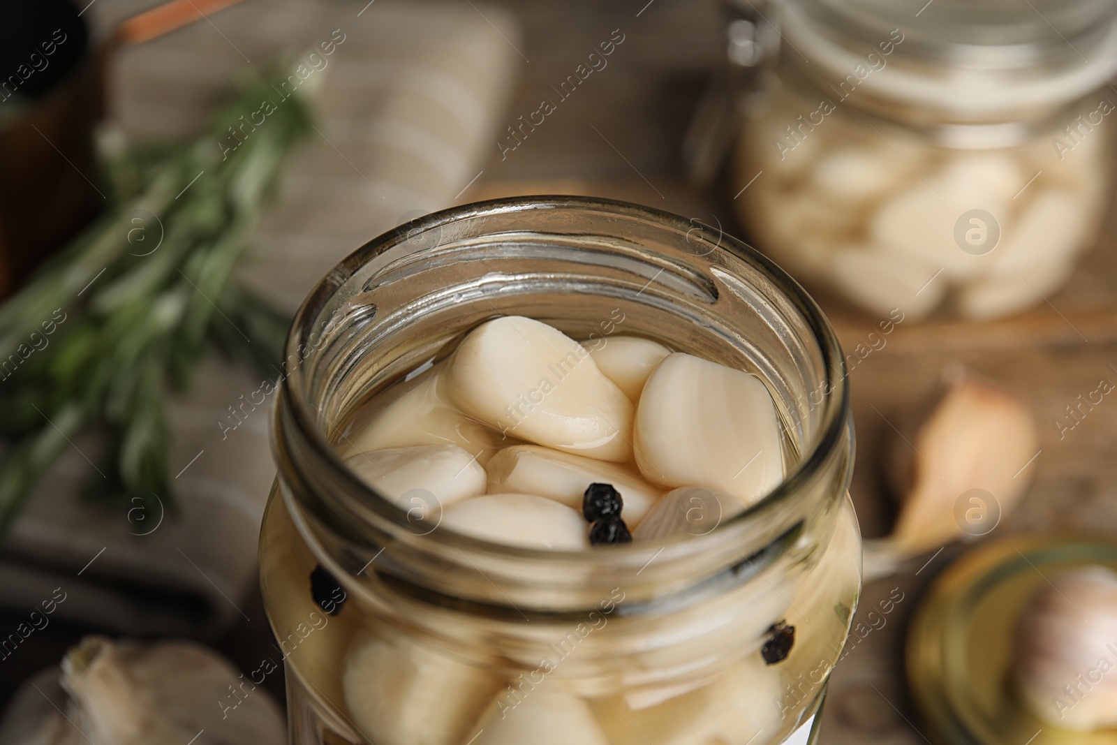 Photo of Jar of pickled garlic on wooden table, closeup