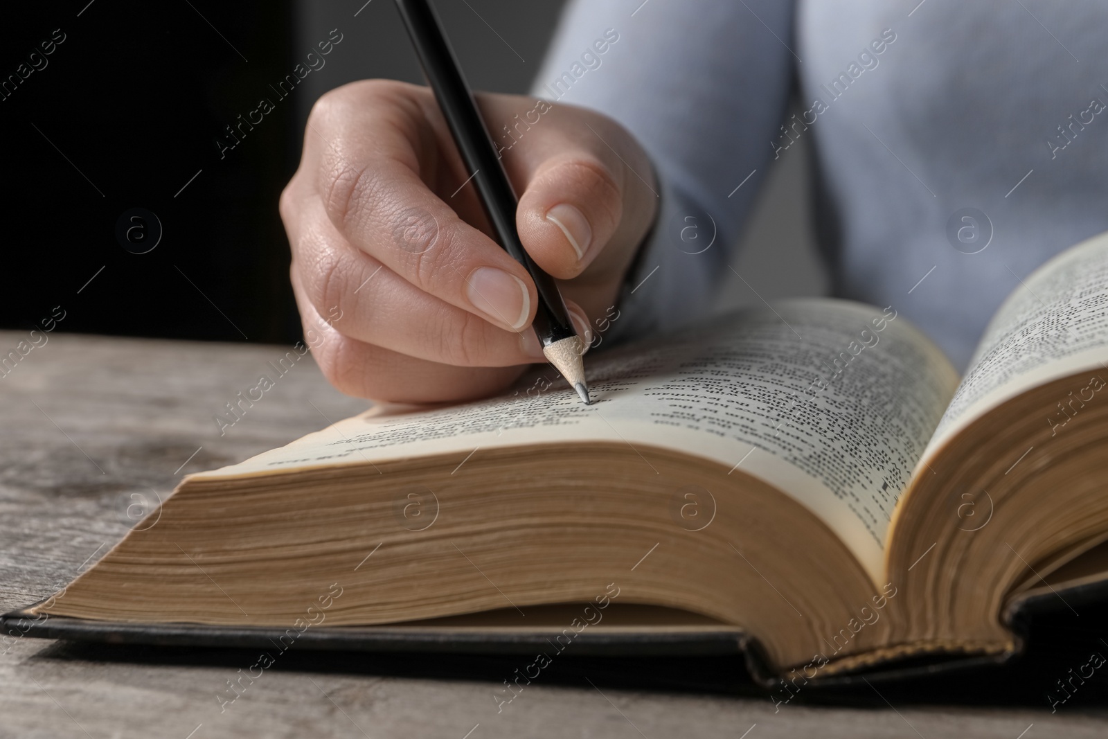 Photo of Woman marking up in Bible at wooden table, closeup