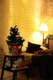 Small fir and Christmas gift in festive room interior