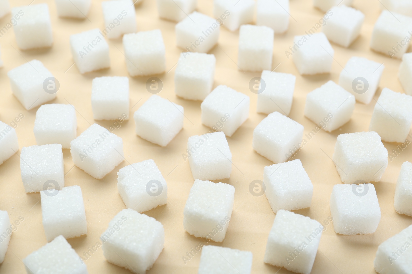 Photo of White sugar cubes on beige background, closeup