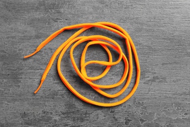 Orange shoelace on grey stone background, top view