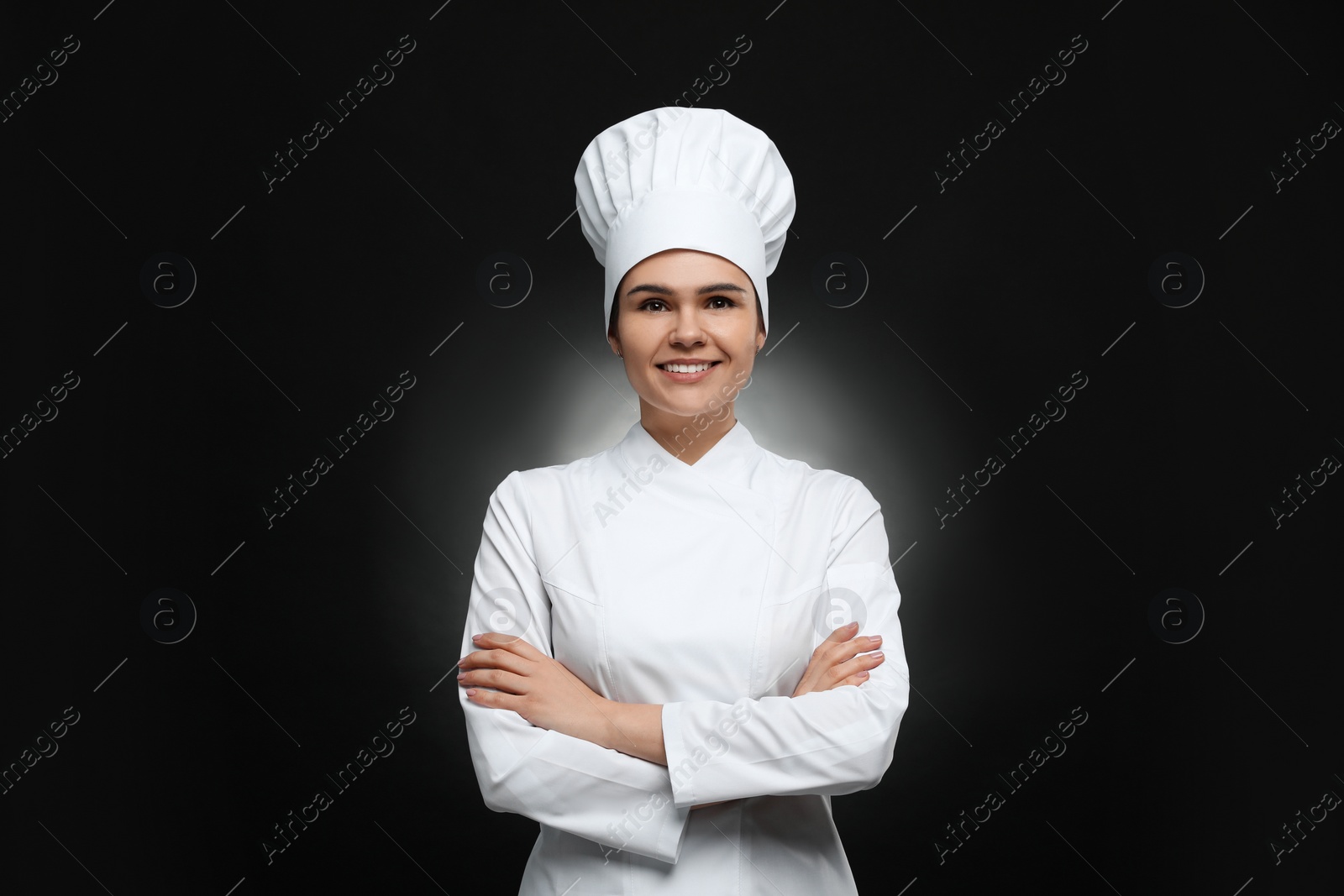 Photo of Happy female chef wearing uniform and cap on black background