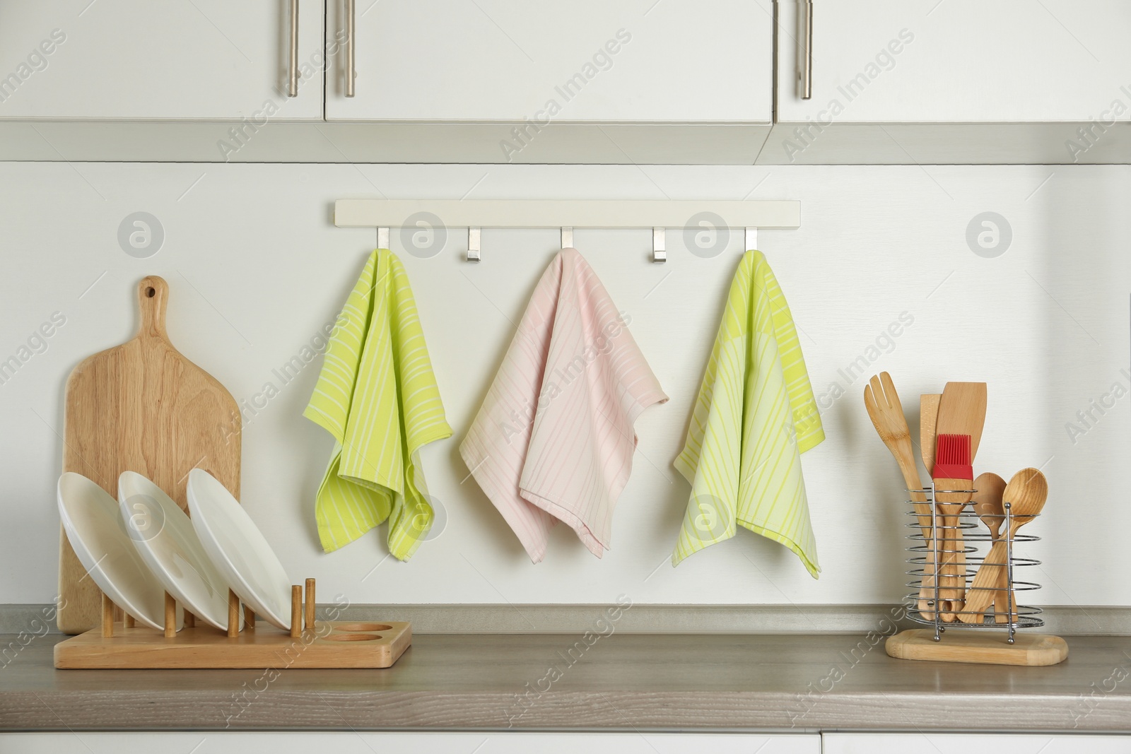 Photo of Different kitchen towels hanging on hook rack indoors