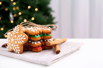Photo of Decorated cookies on white table against blurred Christmas lights. Space for text
