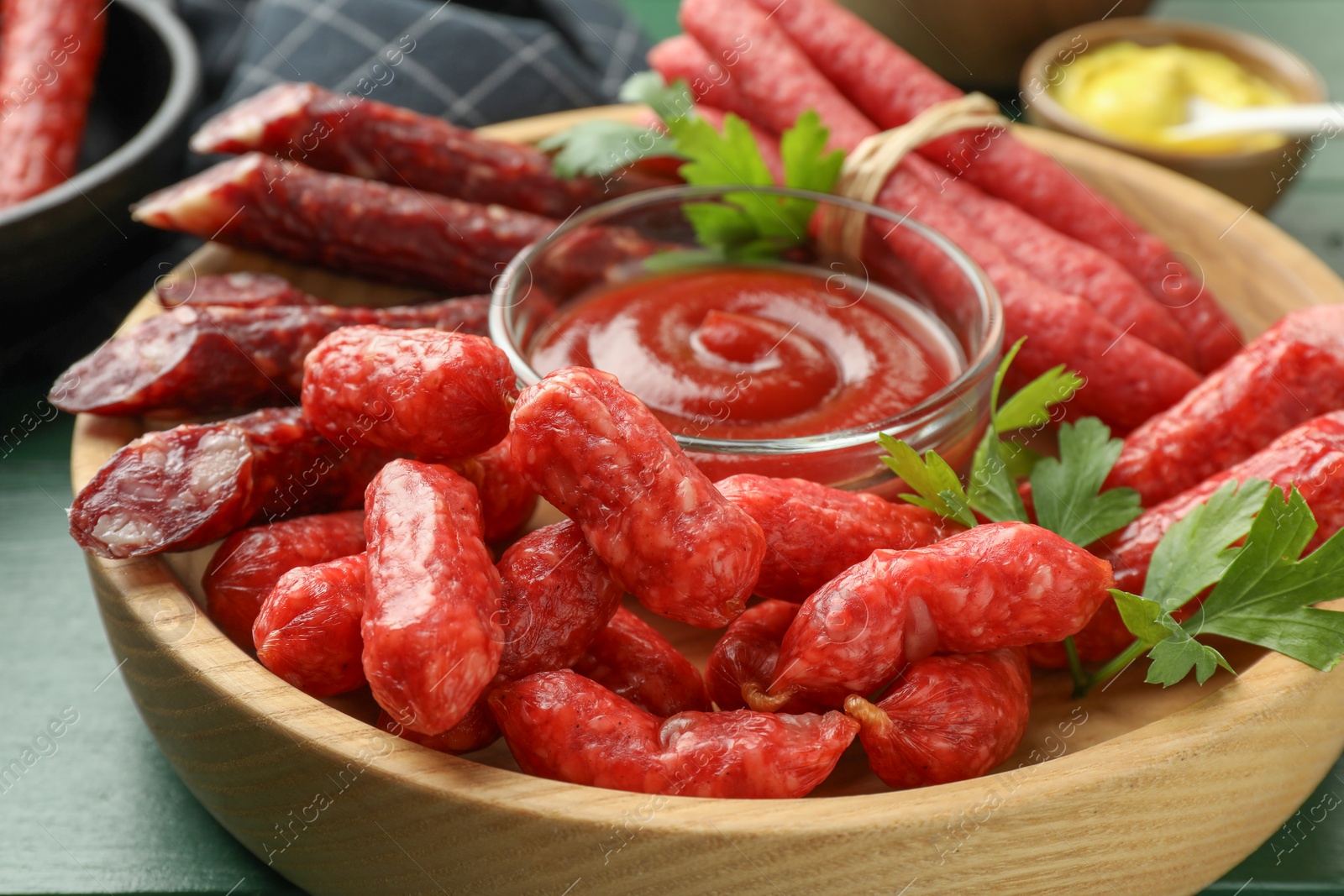 Photo of Different thin dry smoked sausages, parsley and ketchup on table, closeup