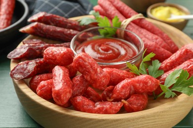 Photo of Different thin dry smoked sausages, parsley and ketchup on table, closeup