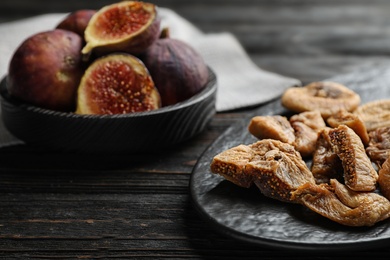 Photo of Slate plate with tasty dried figs on black wooden table, closeup. Space for text