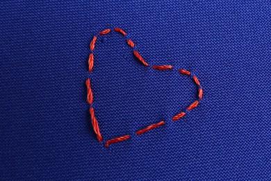 Photo of Embroidered heart on blue cloth, top view