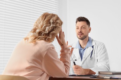 Photo of Doctor consulting patient at table in clinic