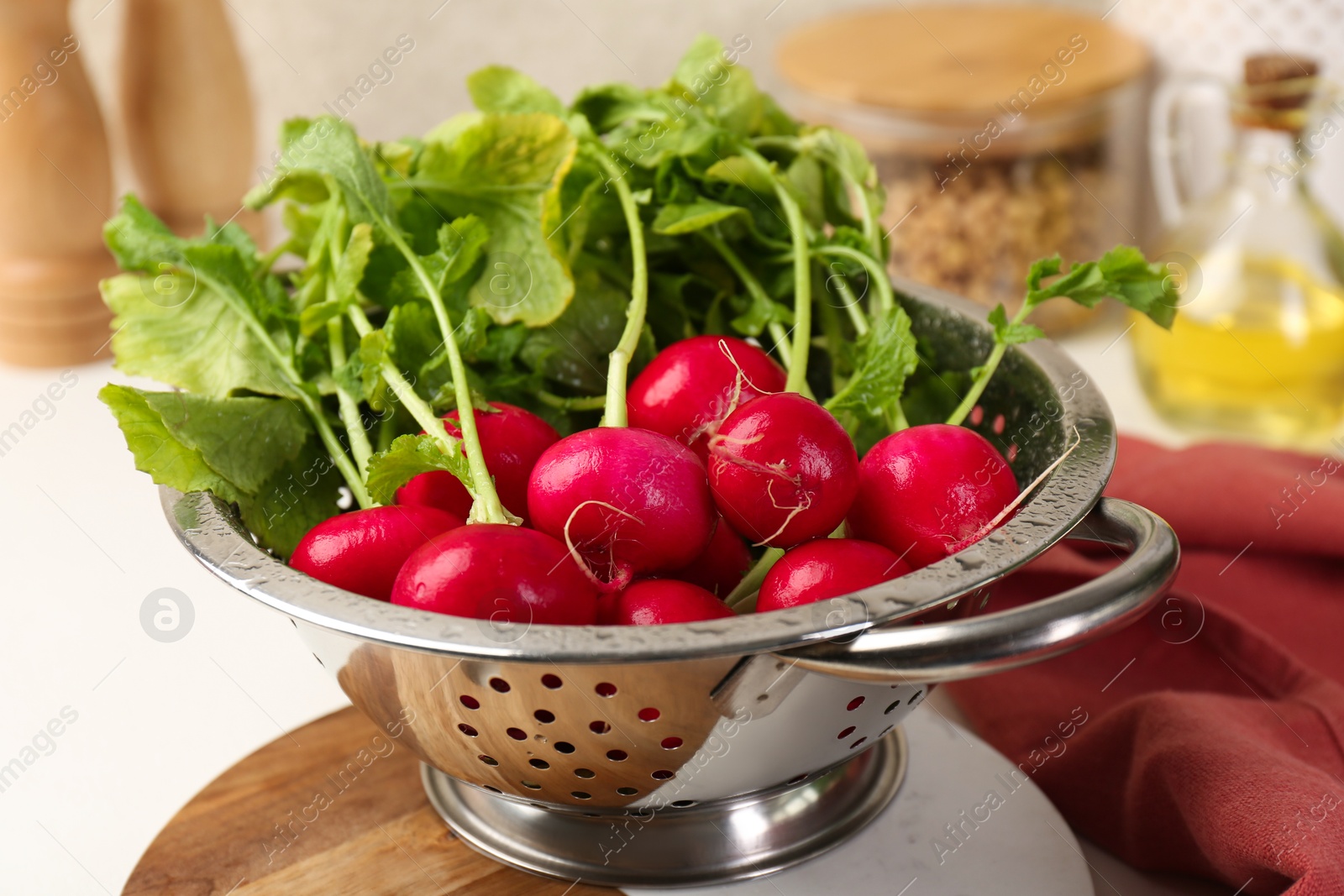 Photo of Wet radish in colander on white table, closeup