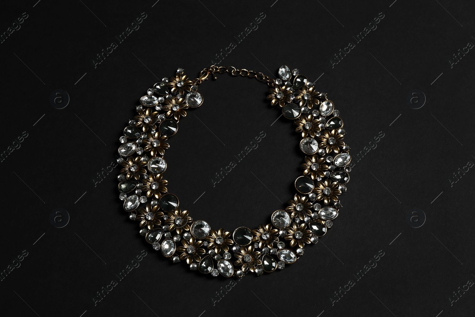 Photo of Stylish necklace with gemstones on black background, top view. Luxury jewelry